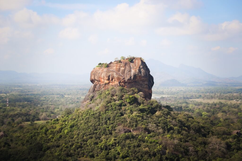 View of the iconic Sigiriya Rock Fortress, surrounded by lush vegetation in Sri Lanka.